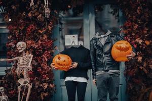 Headless couple holding pumpkin heads by the door on the street photo