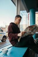 retrato de un hombre sentado en un café, leyendo periódicos y bebiendo café foto