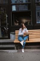 Beautiful young woman in street cafe drinks coffee photo