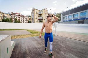 Muscular guy with a naked torso in outdoor street gym. photo