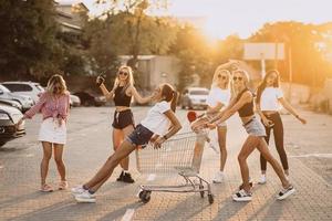 las mujeres jóvenes con un carrito de supermercado se divierten foto