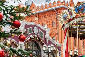 Moscow, Russia, 2021 - Christmas decorated Manezhnaya Square and merry go round. Many christmas trees on Red Square background. photo