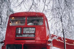 amorosa pareja joven besándose en el autobús rojo, disfrútense unos a otros foto