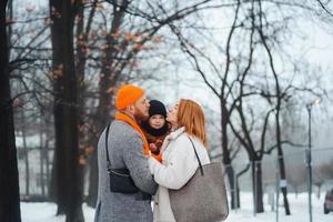 papá mamá y bebé en el parque en invierno foto