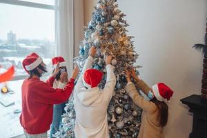 A young people decorates the Christmas tree in medical masks. photo
