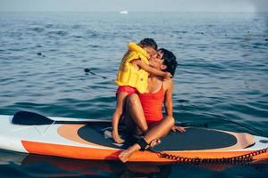 madre con hija en una tabla de paddle foto