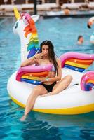 Woman on inflatable unicorn toy mattress float in pool. photo