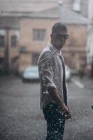 Portrait of carefree handsome young man is feeling free under the rain photo