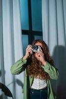 Cheerful young woman making photo on camera at home