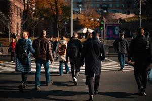 Lots of people crossing the street at the traffic lights. photo