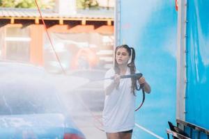 Brunette from a high-pressure hose washes the car at a car wash photo