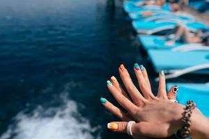 Women beautiful manicure in the pool. Close up photo