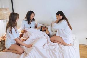amigas jóvenes positivas en el interior de la cama en la despedida de soltera en casa. foto