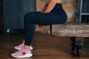 mujer deportiva en ropa deportiva descansando en un banco en el gimnasio. foto