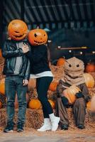 A guy and a girl with a pumpkin heads posing at the scarecrow photo