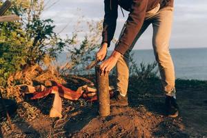 Man chops wood with a large bonfire knife on a sunny day. photo