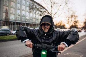 mujer en una chaqueta en un scooter eléctrico en una ciudad de otoño. foto