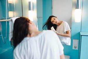 Portrait of young woman using hairdryer in bathroom photo