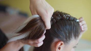 Process of braiding. Master weaves braids on head in a beauty salon, close up photo