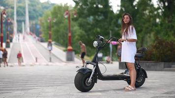 Young beautiful woman and an electric scooter, ecological transport photo