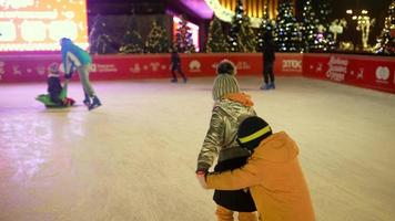 People enjoy ice skating in the street around Christmas tree in rink. photo