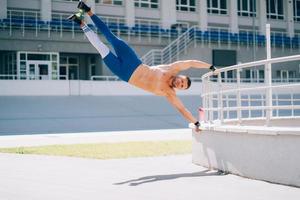 Young athletic man performs gymnastic elements - human flag. photo