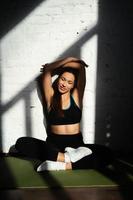 Fit woman resting after home workout, sitting on mat photo