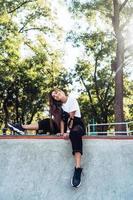 Beautiful young hipster girl sitting on the edge of a ramp photo