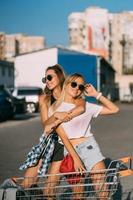 Two young girls in sunglasses posing for the camera on the car parking. photo