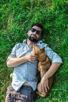 Top view of man and dog lying on green grass. Attractive European man is hugging his dog. photo