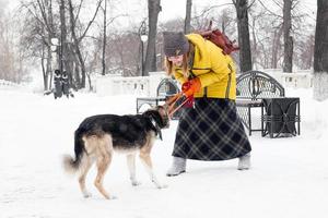 Beautiful smiling young woman is playing with her dog in a snowy winter park. photo