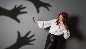 terrified woman in defensive posture is attacked by shadows of hands photo