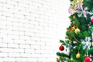 Christmas and New Year holiday concept. Closeup and blur Christmas tree decoration with ribbons balls and ornaments over white brick wall and bokeh photo