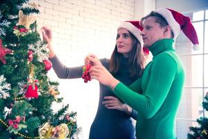 Merry Christmas and New Year concept. Young Caucasian lover with christmas theme clothing celebrate decorating chrismas tree and talk with laugh love and fun in the party at home photo