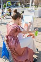 Moscow, Russia, 2019 - Young woman and little girl paint easter kulich at workshop outdoors.  Easter Holiday festival in Moscow. photo