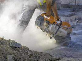 A worker cuts a tile to size with an electric grinder with many smoke. Pollution concept photo