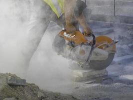 A worker cuts a tile to size with an electric grinder with many smoke. Pollution concept photo