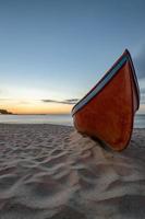 beauty morning with the lonely red boat on the sea beach. Vertical view photo