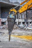 Arm of excavator with hydraulic breaker hammer for the destruction of concrete and hard rock at the construction site. Demolition equipment photo