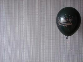 Black balloon with words HAPPY BIRTHDAY on yellow background, space for text photo