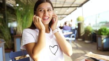 mooi jong vrouw Bij buiten tafel gebruik makend van telefoon video