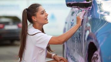 mujer joven lavando auto con espuma rosa video