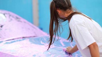 Young woman washing car with a pink foam video