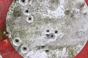 Detailed close up of bullet holes from gun shots in a traffic sign photo