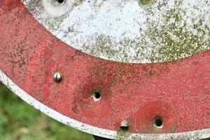 Detailed close up of bullet holes from gun shots in a traffic sign photo