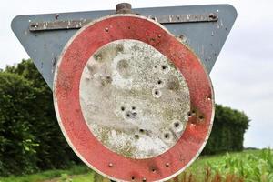 Detailed close up of bullet holes from gun shots in a traffic sign photo