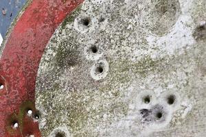 Detailed close up of bullet holes from gun shots in a traffic sign photo