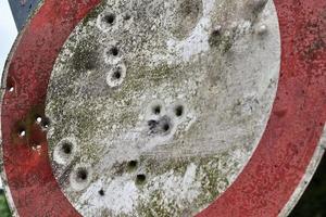 Detailed close up of bullet holes from gun shots in a traffic sign photo