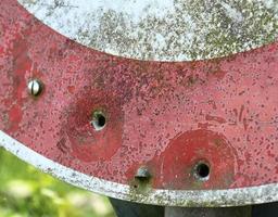 Detailed close up of bullet holes from gun shots in a traffic sign photo