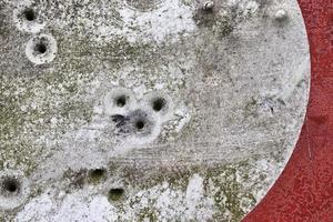 Detailed close up of bullet holes from gun shots in a traffic sign photo